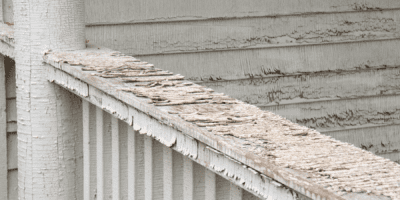Close-up of a weathered, peeling wooden fence top outdoors.